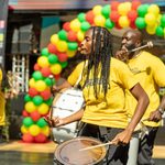 Men drumming on steel pans in front of a balloon archway