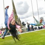 A male and female acrobat performing on a giant swingset in front of St Martin's Church in the Bullring