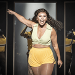 A Chorus Line Production shot. Mireia Mambo (Richie Walters) walking towards the front of the stage. She is pointing behind her and singing passionately.