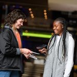 A young person scanning a ticket with a member of staff.