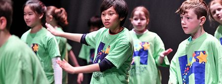 A group of children in green t-shirts dancing.