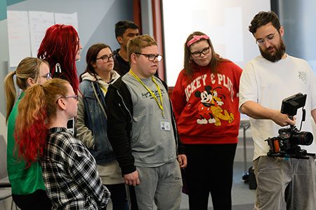 A group of young people being shown how to use a camera.