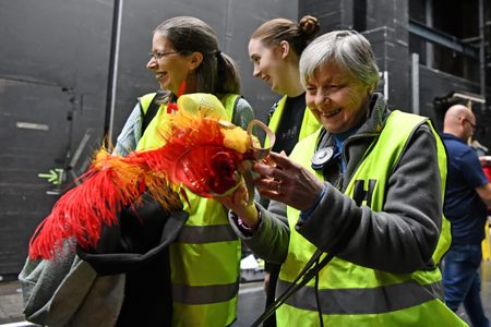 Photo of Touch Tour participant holding a feathered headdress on Birmingham Hippodrome's Everybody's Talking About Jamie Touch Tour