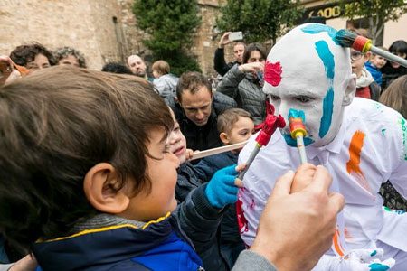 Blanko Weekender image. Blanko is painted in white and young children are painting his face with fun, colourful paints.