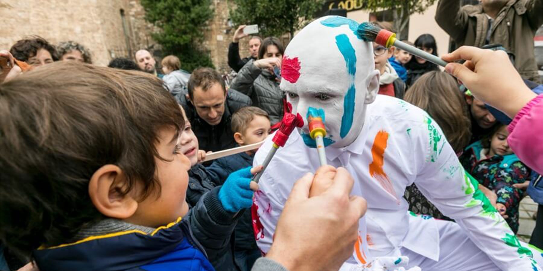 Blanko Weekender image. Blanko is painted in white and young children are painting his face with fun, colourful paints.