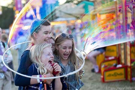 Bubble Inc Weekender images. Three young children are laughing happily as someone traps them in a massive bubble.