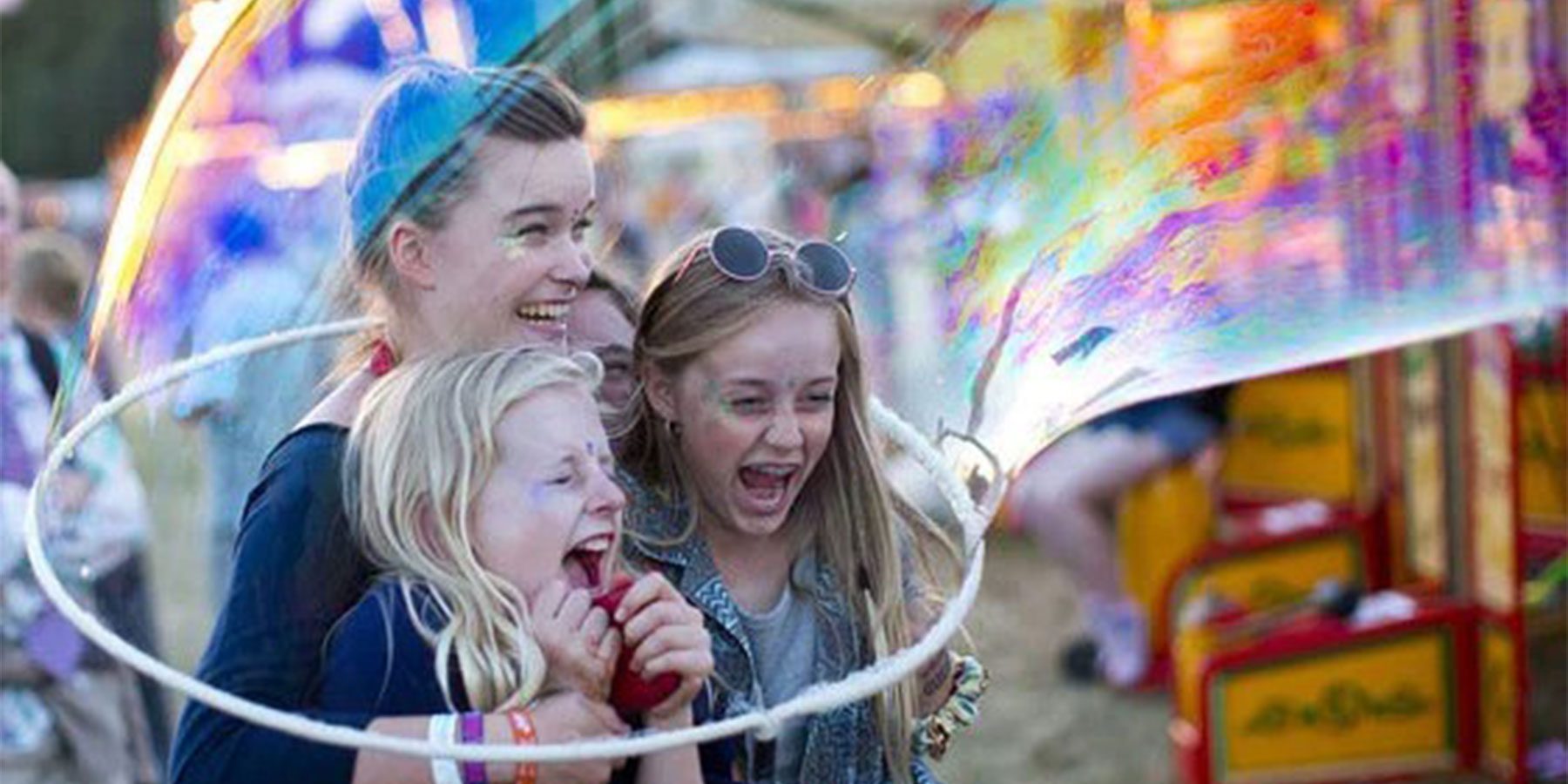 Bubble Inc Weekender images. Three young children are laughing happily as someone traps them in a massive bubble.