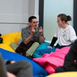 Two people sit and chat atop a group of bean bags.