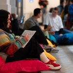 Person sits on a bean bag writing in notebook.