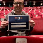 Person smiles while looking into camera holding certificate with Name a Seat information.