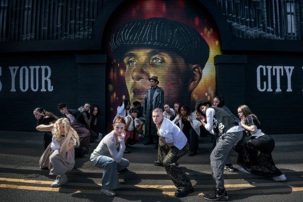 Group of dancers hold poses in front of Peaky Blinders mural in the city.