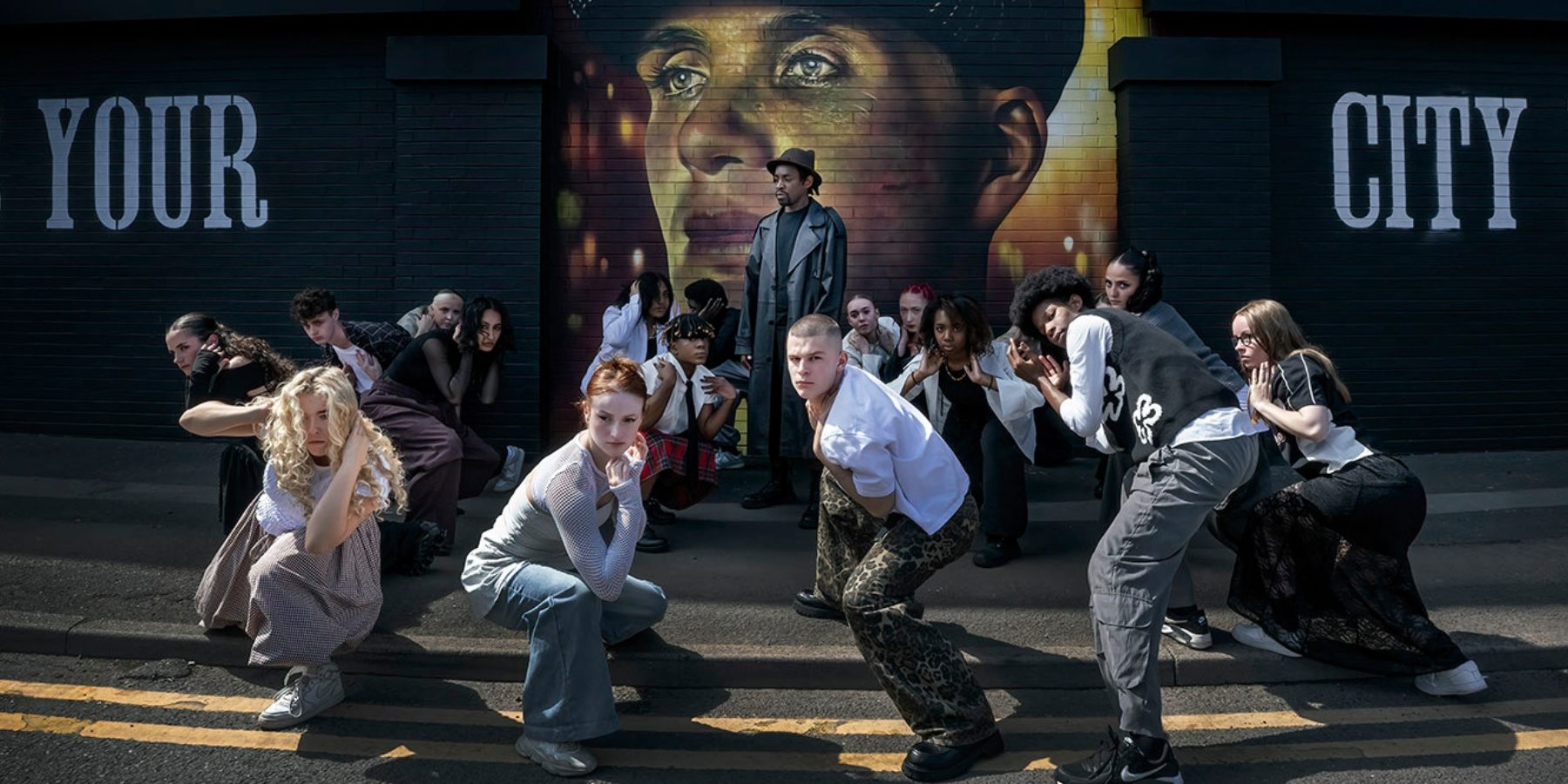 Group of dancers hold poses in front of Peaky Blinders mural in the city.