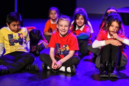 Children sitting on stage during an a HEN Network activity.