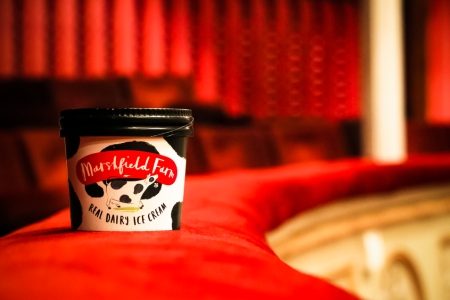 Ice cream tub sits on edge of balcony in theatre.