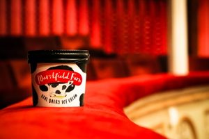 Ice cream tub sits on edge of balcony in theatre.