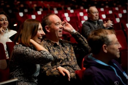 Group of people sit together in the audience as they enjoy a Backstage Tour of the theatre.