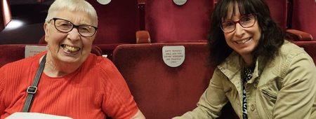 Carol and Daphne sit together in the Main Theatre next to their Named Seat